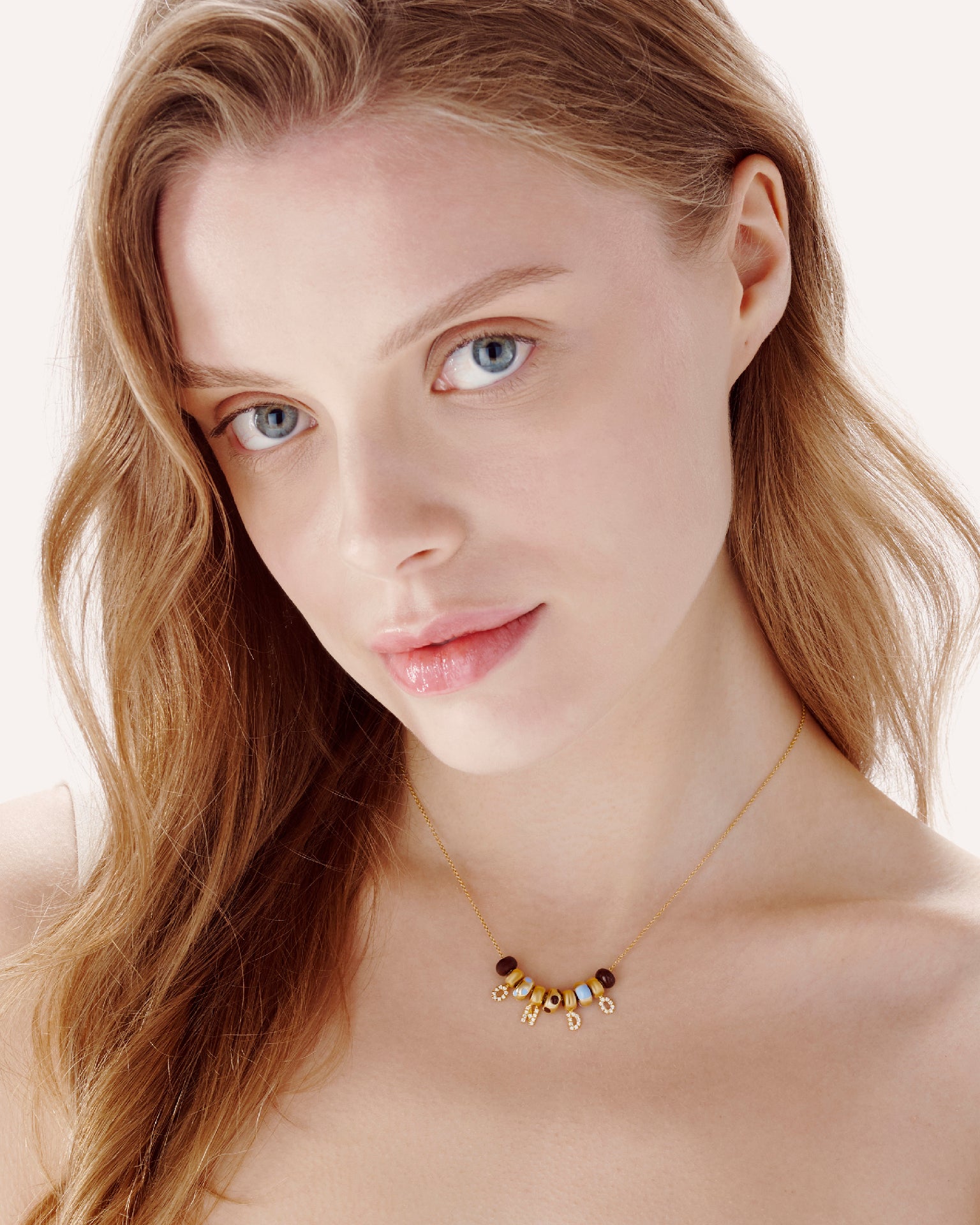 Model wearing an ONDO necklace with colorful enamel beads and gold letter charms spelling "ONDO", showcasing personalized and playful fine jewelry.